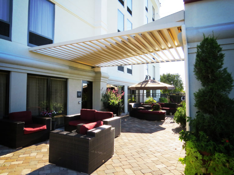 This image depicts a white Mapes aluminum canopy being used in a commercial outdoor design.
