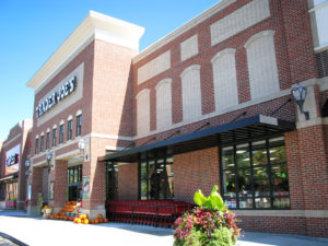 This image depicts the outside view of a grocery store with a black canopy and brick siding.