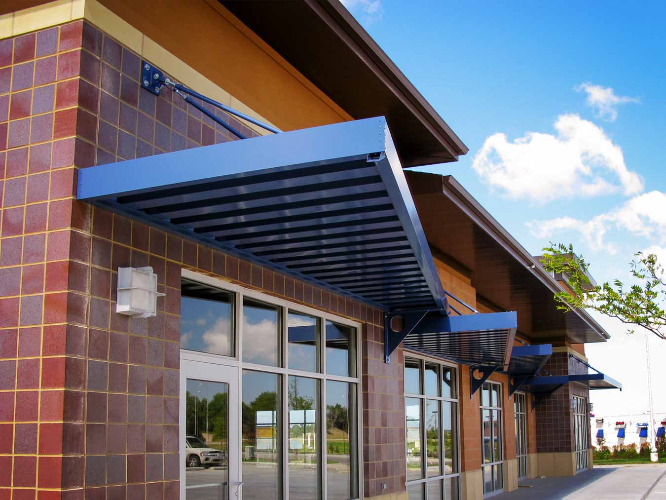 Metal Canopies: Choosing Steel vs. Aluminum for Durable Design This image depicts a retail building with a blue metal canopy.