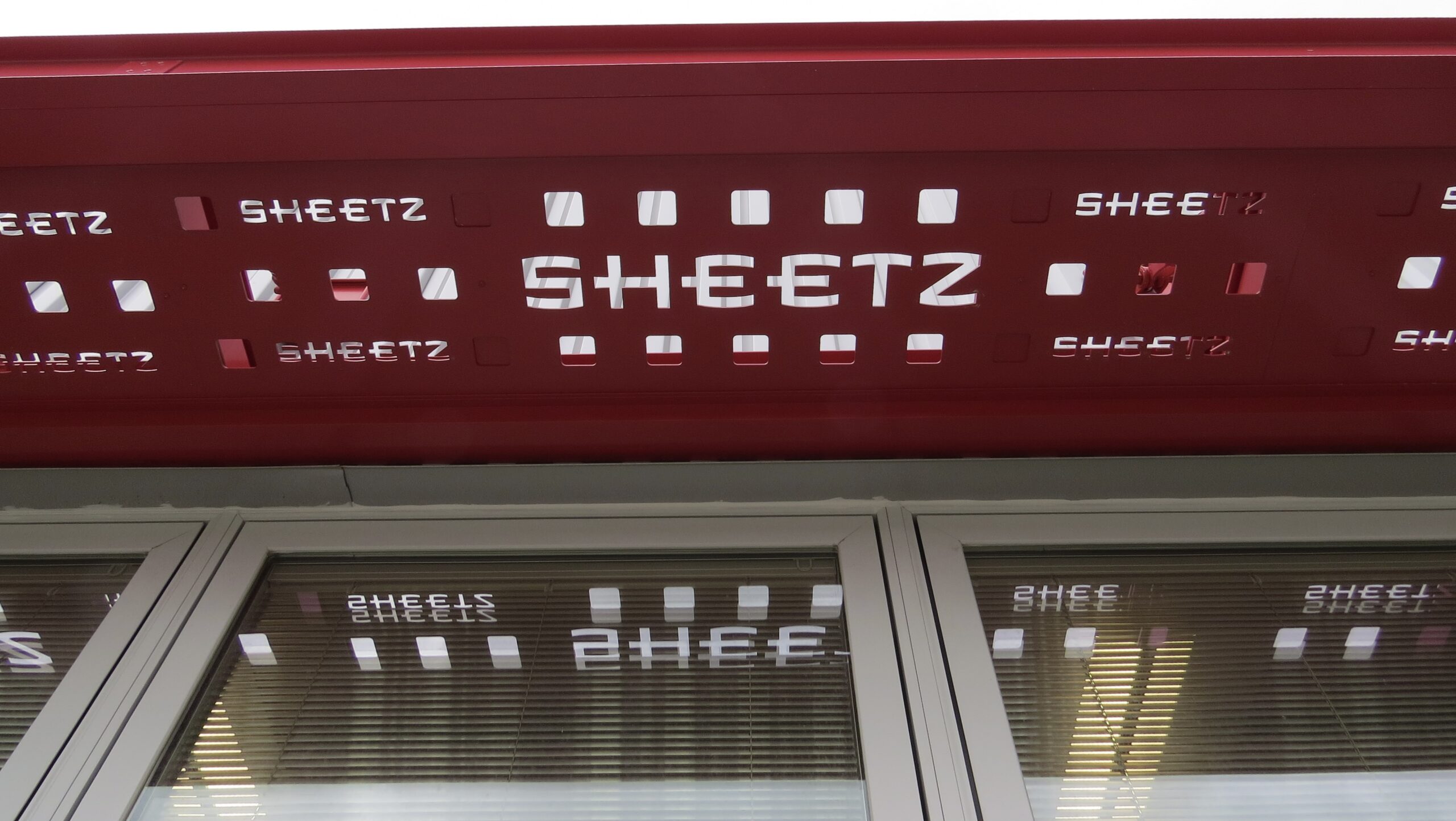 A Sheetz storefront has a customized canopy with perforated decking showcasing their branding.