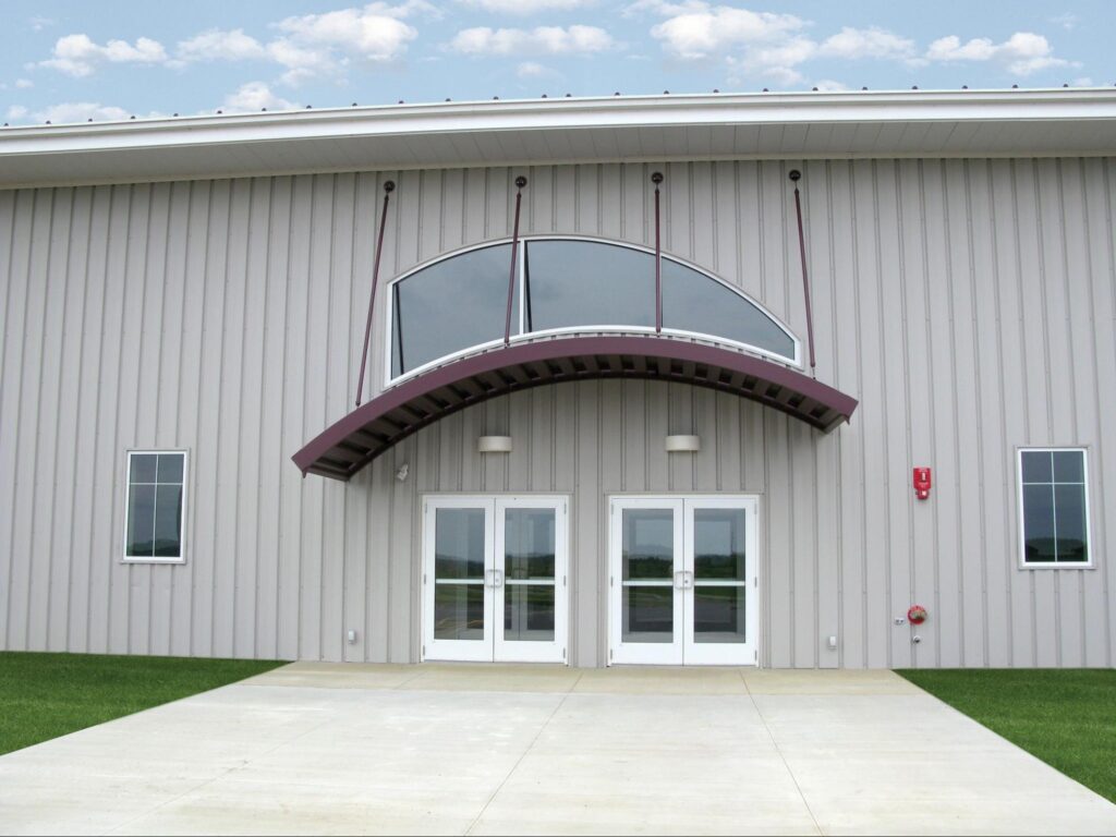 A commercial building has a maroon curved canopy. 